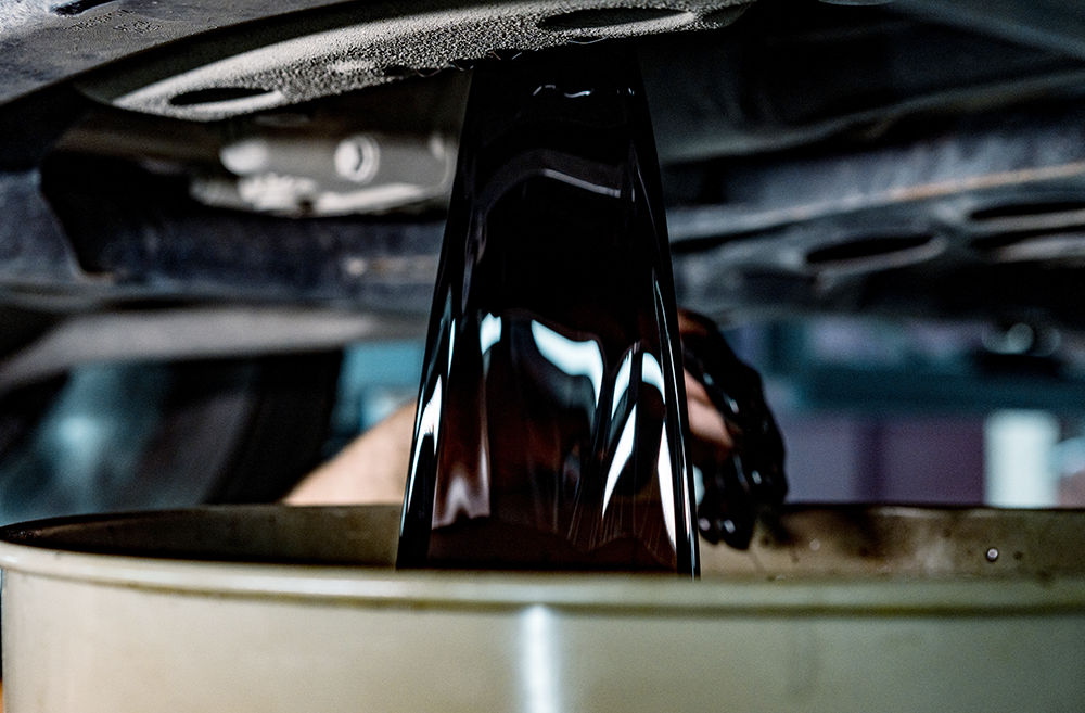 Used engine oil draining from a vehicle into an oil pan.